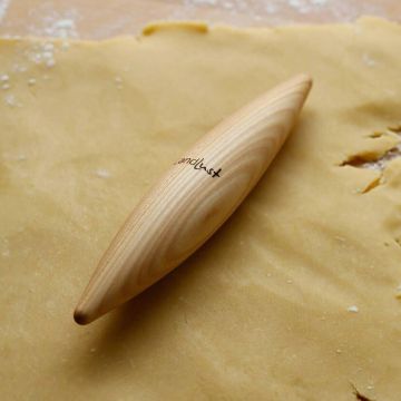 Ein konisch geformter Holz-Teigroller liegt auf ausgerolltem Teig; auf dem Roller ist das Logo „Landlust“ sichtbar.